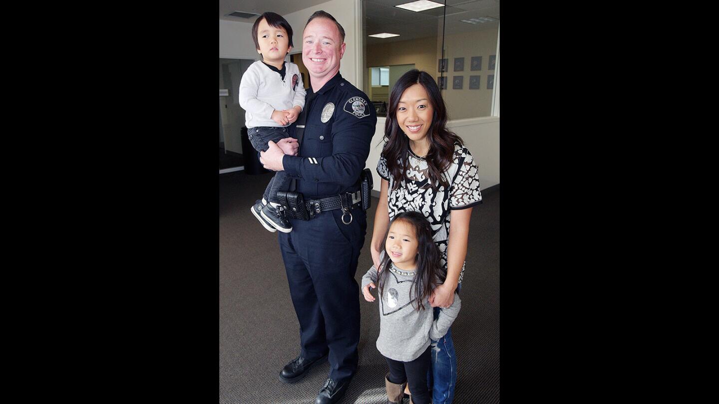 Glendale Police Officer James Colvin holds Clayton Cha, 3, of Glendale, next to mother Jennifer Cha, and Clayton's sister Camryn, 6, at the Glendale Police Department on Thursday, Jan. 22, 2016. Last April, Colvin was the first on the scene to treat then 2-year-old Clayton, who had fallen on his head from 22-feet onto concrete.