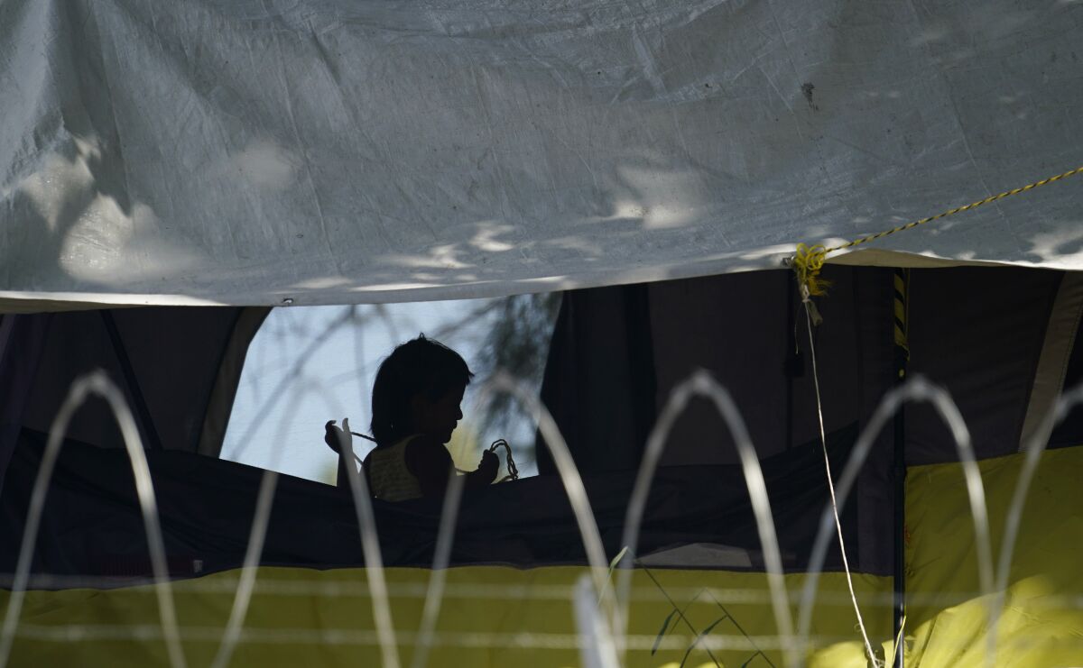 FILE - In this Nov. 18, 2020, file photo, a young girl plays in her family's tent at a camp of asylum seekers stuck at America's doorstep, in Matamoros, Mexico. Increasing numbers of parents and children are crossing the border, driven by violence and poverty in Central America and growing desperation in migrant camps in Mexico. U.S. Customs and Border Protection said Monday, Dec. 14, 2020 that it made 4,592 apprehensions of unaccompanied immigrant children in November, more than six times the figure in April. (AP Photo/Eric Gay File)