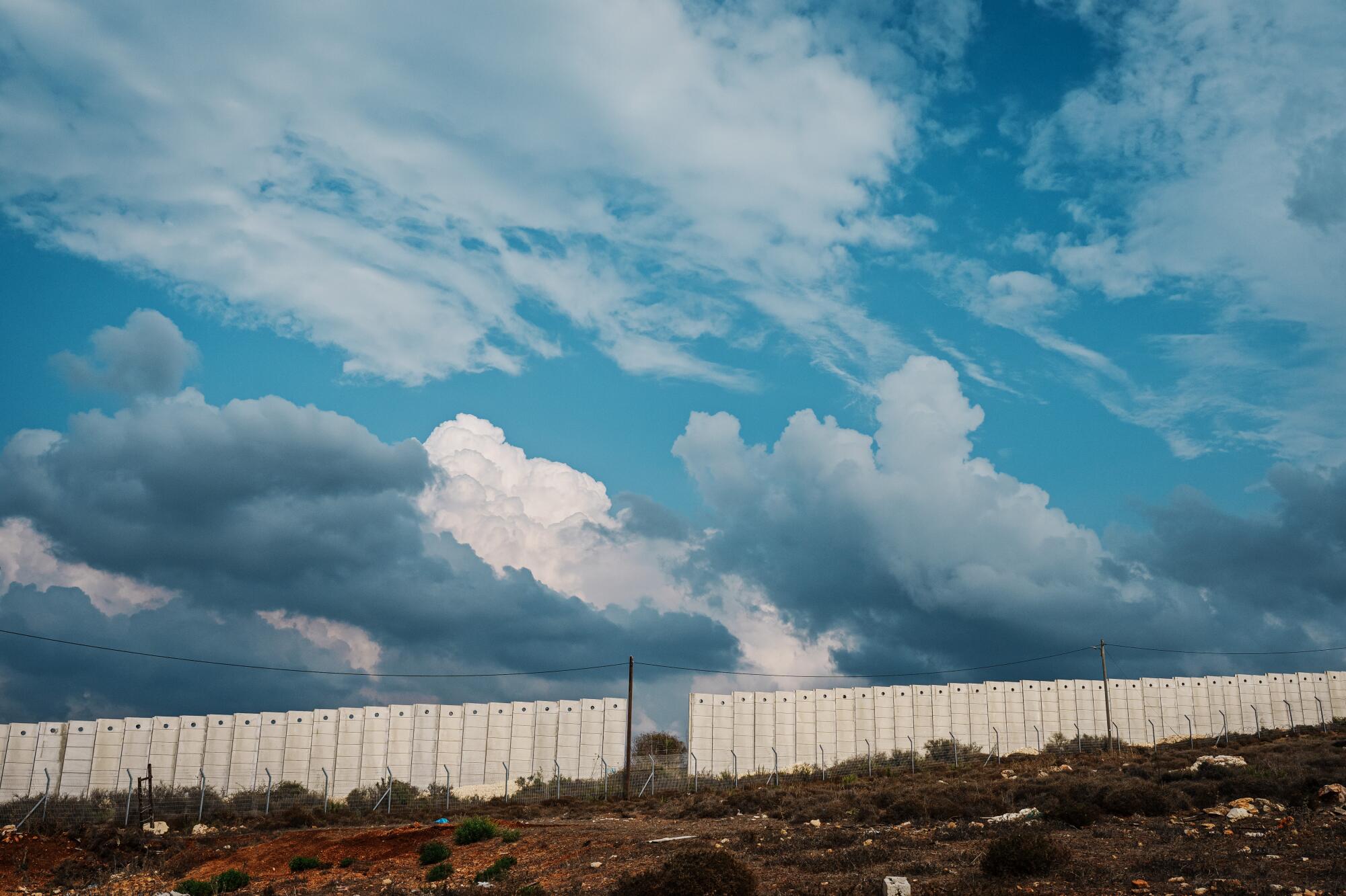 A white border fence seen against blue skies and clouds