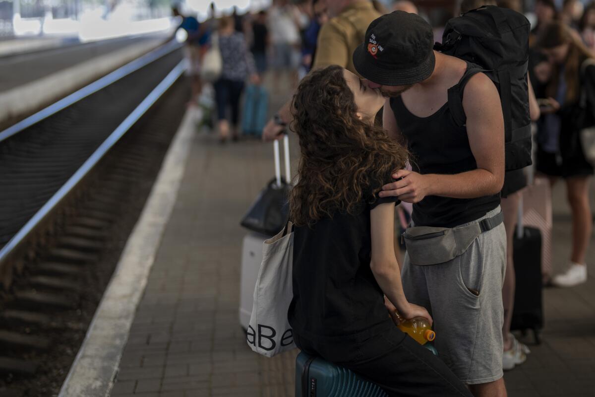 A couple kiss on a train station platform