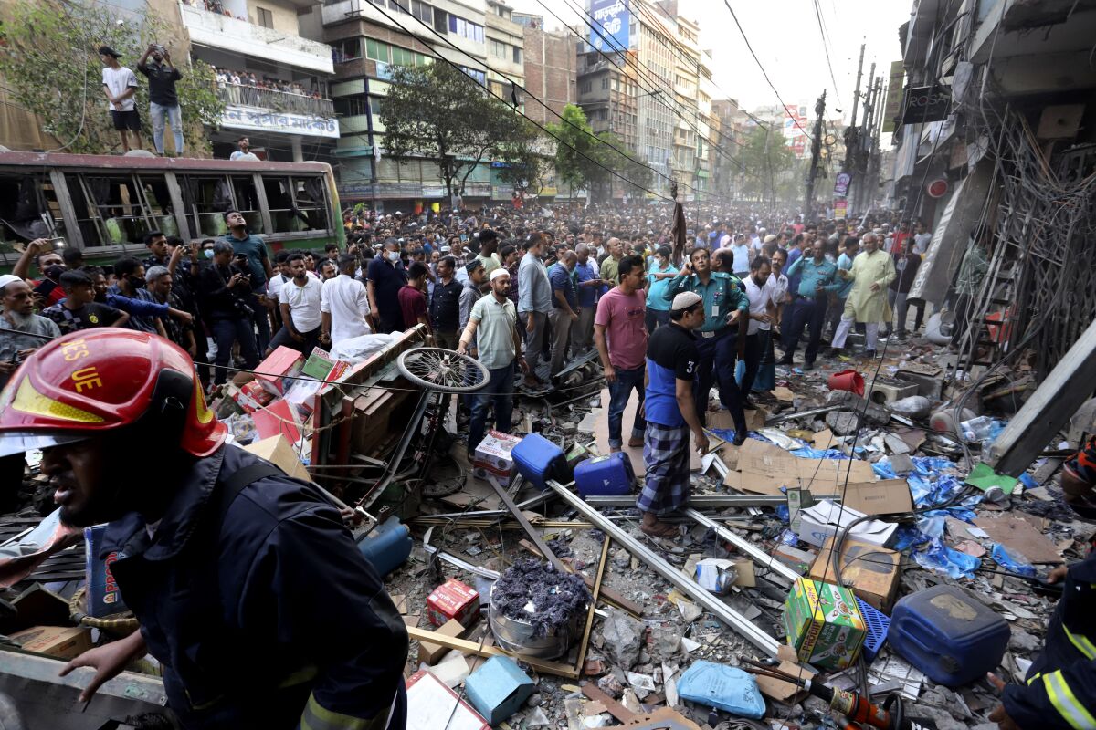 Onlookers gather outside the site of an explosion, in Dhaka, Bangladesh, Tuesday, March 7, 2023. An explosion in a seven-story commercial building in Bangladesh's capital has killed at least 14 people and injured dozens. Officials say the explosion occurred in a busy commercial area of Dhaka. (AP Photo)