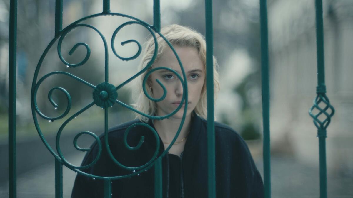 A woman looks through a fence 