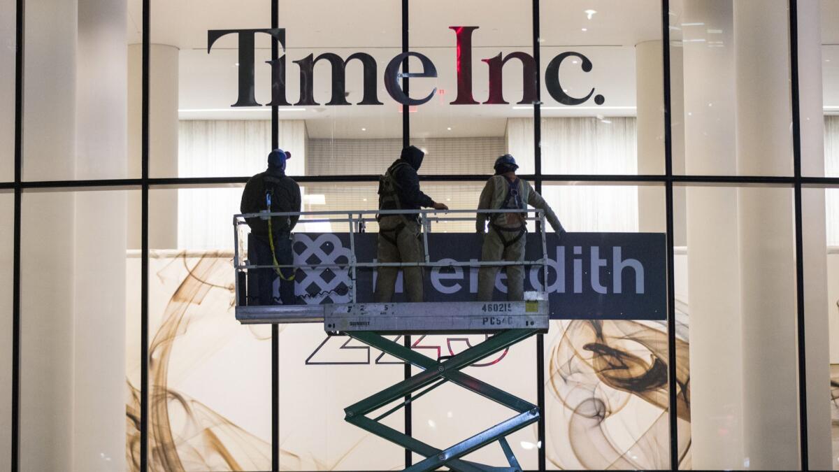Workers prepare to cover up Time Inc. signage with Meredith Corp. signage in New York on Jan. 31.