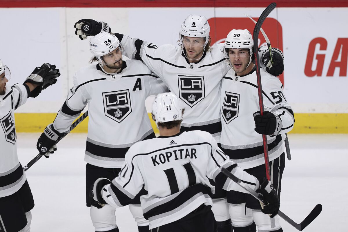 Los Angeles Kings center Adrian Kempe (9) is surrounded by teammates in celebration after scoring a goal against the Minnesota Wild during the first period of an NHL hockey game, Sunday, April 10, 2022, in St. Paul, Minn. (AP Photo/Stacy Bengs)