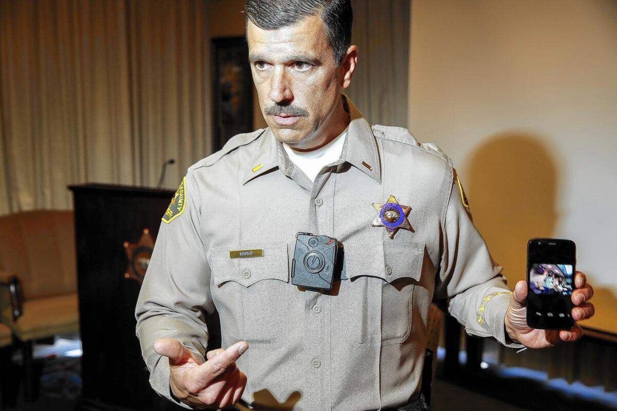 Los Angeles County sheriff's Lt. Chris Marks demonstrates the Taser Axon Flex used by some deputies. It can be clipped onto sunglasses, caps, helmets or collars.