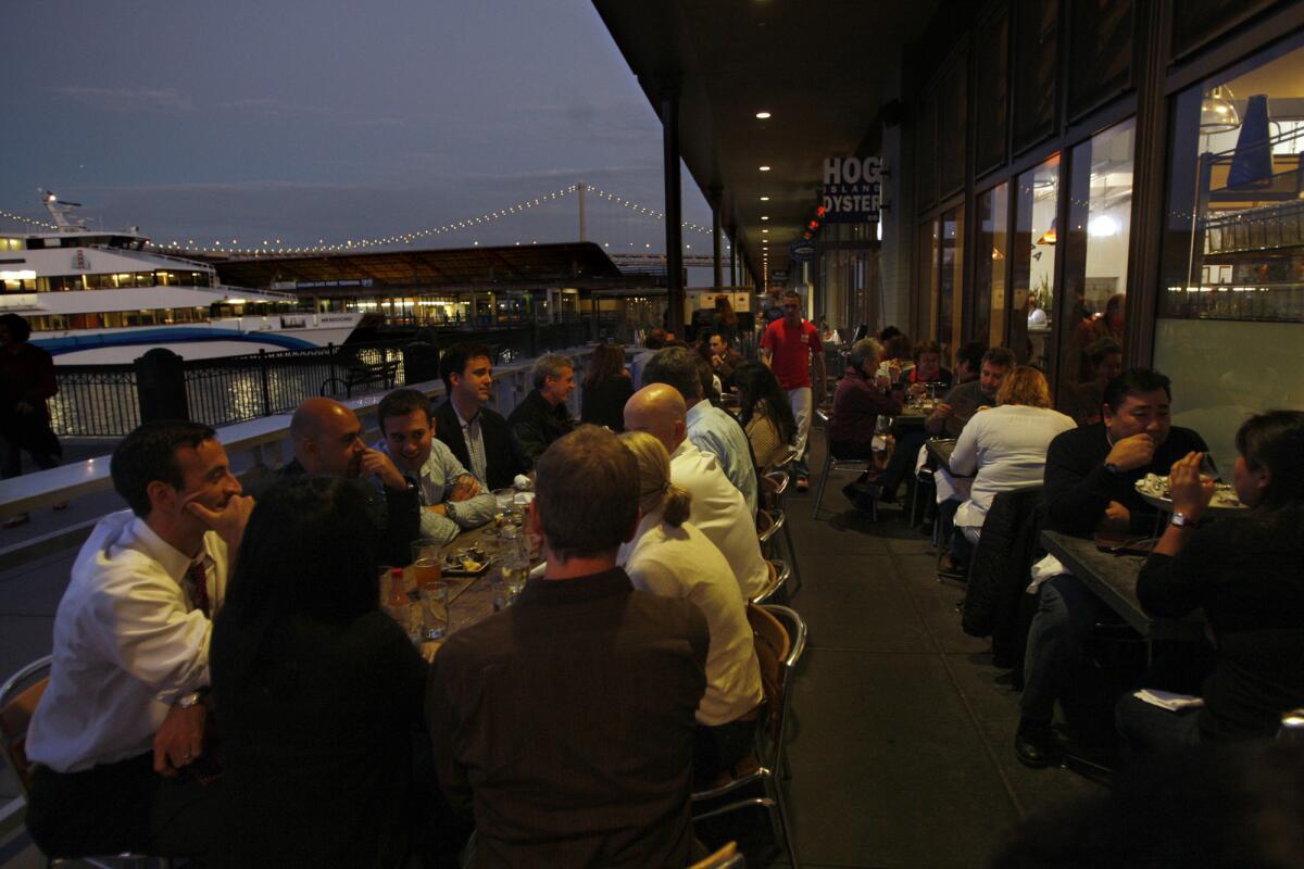 Molina, Genaro -- B58754138Z.1 SAN FRANCISCO, CA -- OCTOBER 1, 2010 -- Customers enjoy their meal on the patio at Hog Island Oyster at the Ferry Building in San Francisco on October 1, 2010. A ferry sits idle, background, as the lights come up on the Bay Bridge. (Genaro Molina/Los Angeles Times)