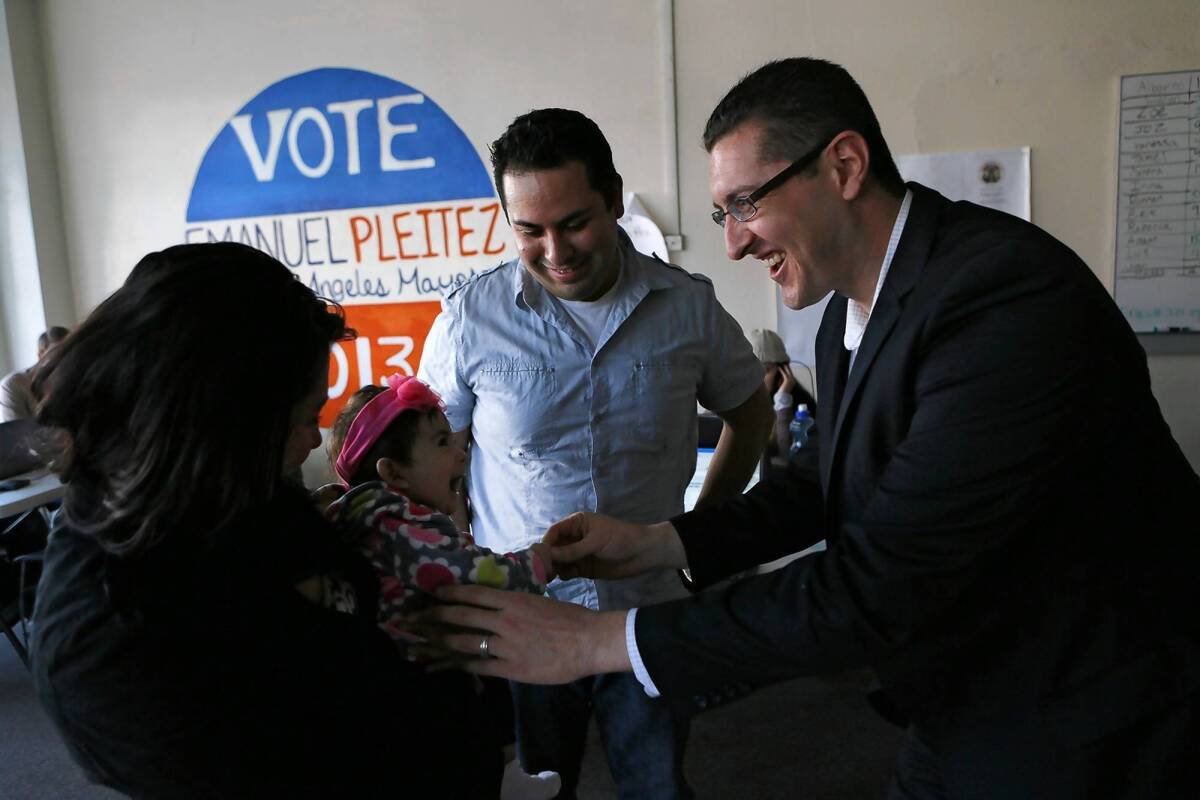 L.A. mayoral candidate Emanuel Pleitez, right, meets Naomi Reyes, the daughter of Jessica Pineda, left, and David Reyes, both of whom are volunteering at Pleitez's campaign headquarters in Boyle Heights.