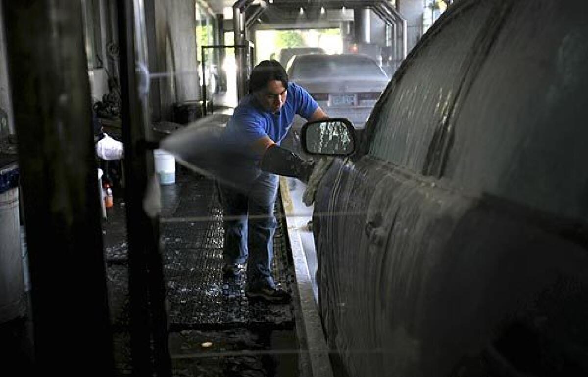 A worker at Blue Wave Car Wash in West Los Angeles washes a vehicle. A Times investigation has found that hand carwashes, automotive beauty shops patronized by tens of thousands of Southern California motorists every day, often brazenly violate basic labor and immigration laws, with little risk of penalty.