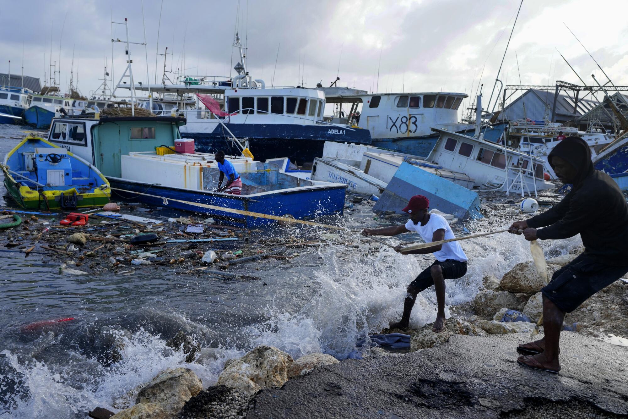 Two people pull a rope tied to a boat in rough waters near other vessels