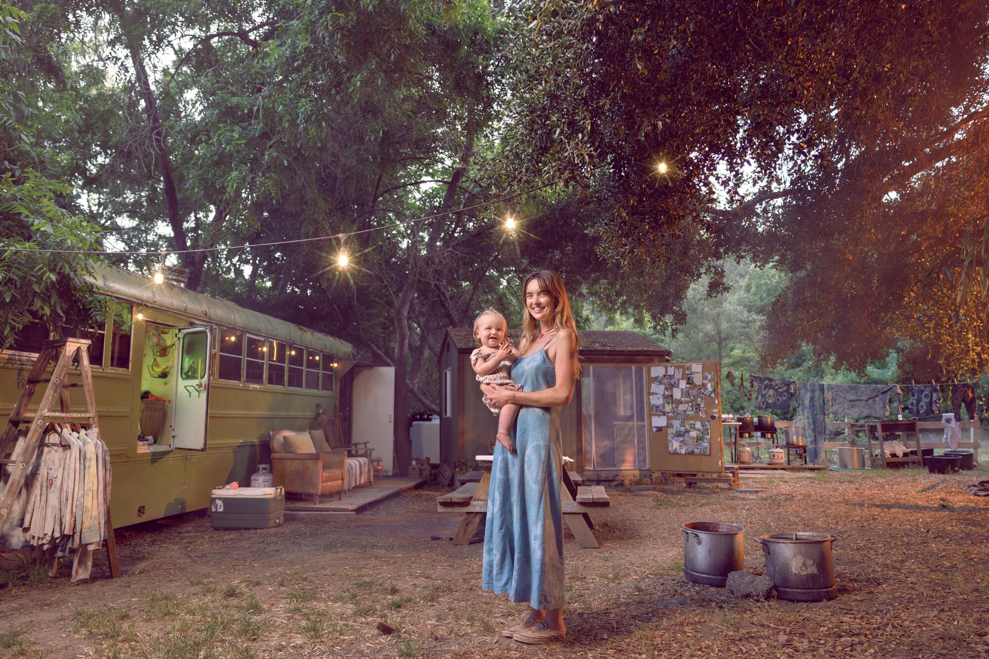 Laura La Rue holds her 16-month-old daughter, Lasca, next to a school bus.