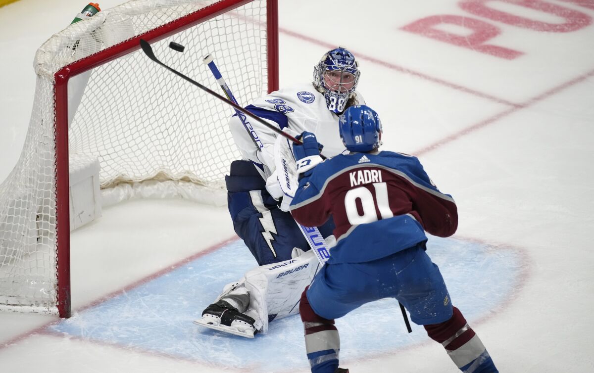 Tampa Bay Lightning goaltender Andrei Vasilevskiy, back, looks to stop a redirected shot by Colorado Avalanche center Nazem Kadri during the third period of an NHL hockey game Thursday, Feb. 10, 2022, in Denver. The Avalanche won 3-2. (AP Photo/David Zalubowski)