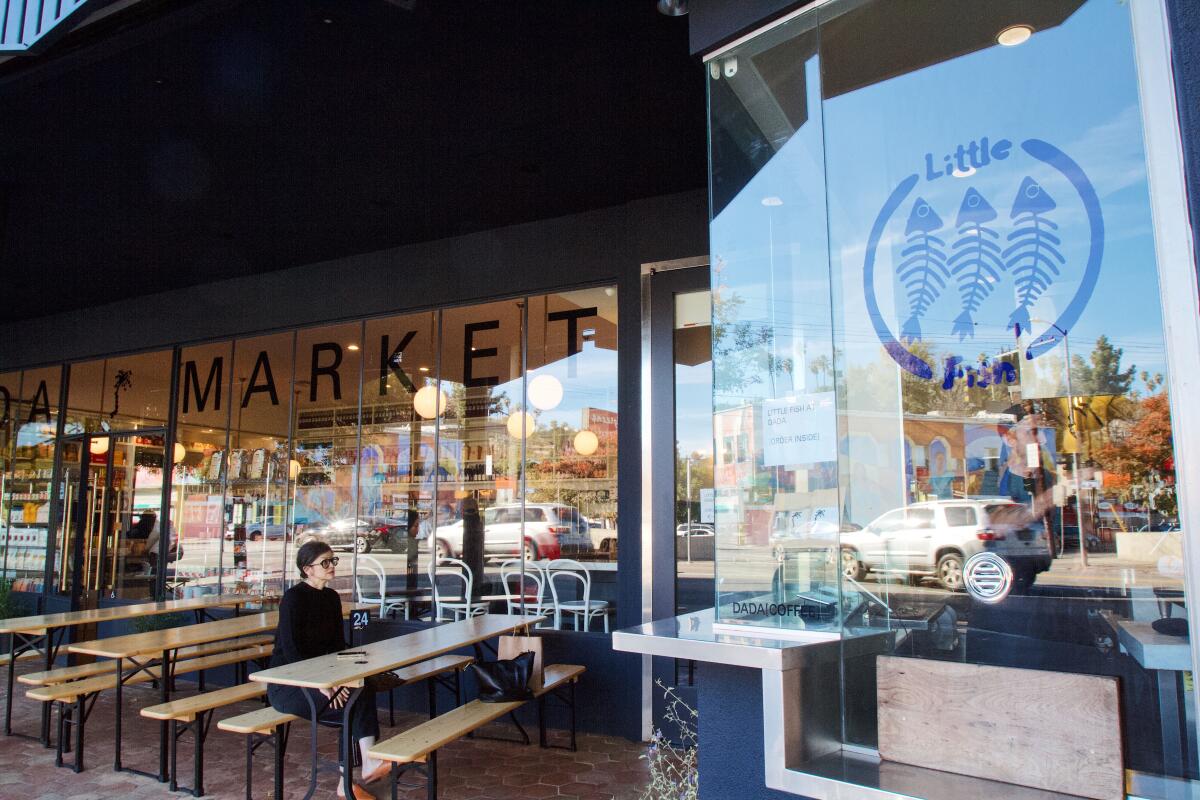 An exterior of Little Fish in Echo Park's Dada Market, picnic benches out front of the windows of both businesses