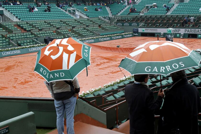 Spectators check out a court at Roland Garros after French Open play was postponed Monday.