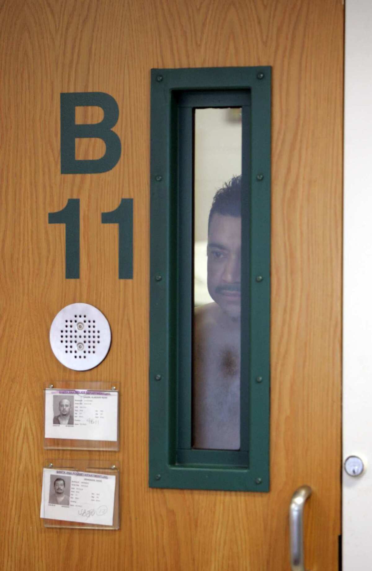 An immigrant detainee peers through the window in his cell at the Santa Ana jail in 2009. The facility no longer houses most people arrested by city police because county jails hold them at no expense to the city.