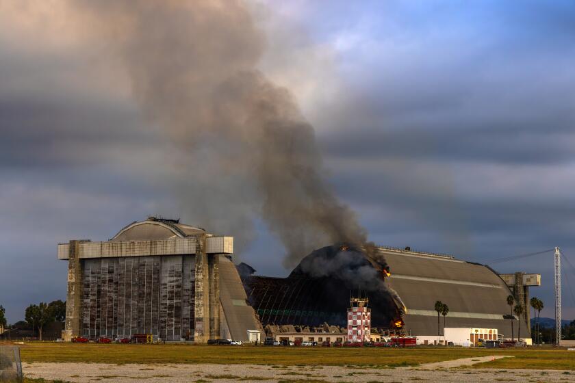 TUSTIN, CA - NOVEMBER 07: A stubborn fire at hangars at the former Tustin Air Base burns Warner Avenue and Legacy on Tuesday, Nov. 7, 2023 in Tustin, CA. (Irfan Khan / Los Angeles Times)