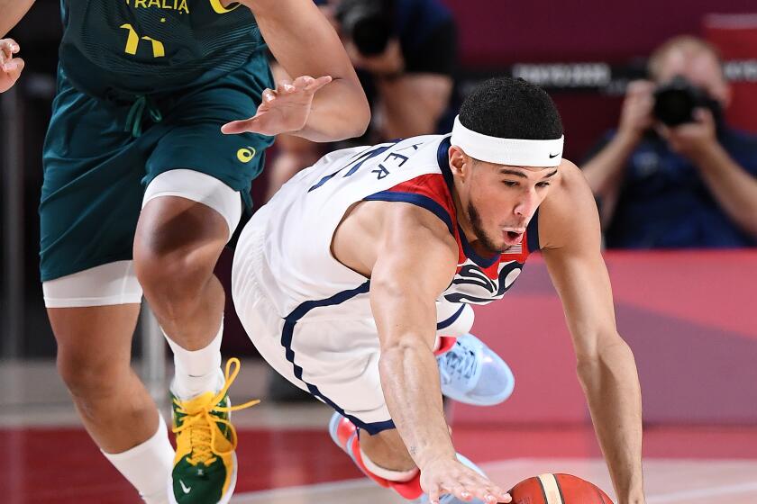 -TOKYO,JAPAN August 5, 2021: USA's Devin Booker dives to steal the ball against Australia's Dante Exum in the second half of a semi-final game at the 2020 Tokyo Olympics. (Wally Skalij /Los Angeles Times)