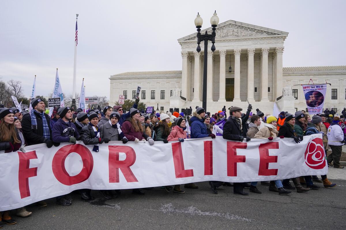 Demonstrators march pas the Supreme Court carrying a large banner, part of which reads "for life"