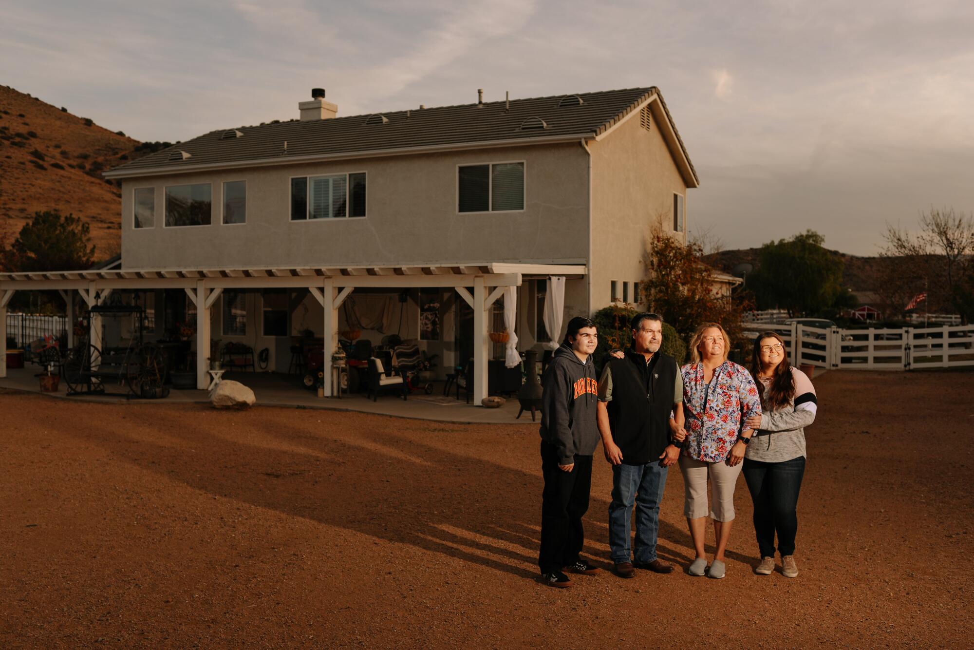 A mother, father, daughter and son stand outside their home.