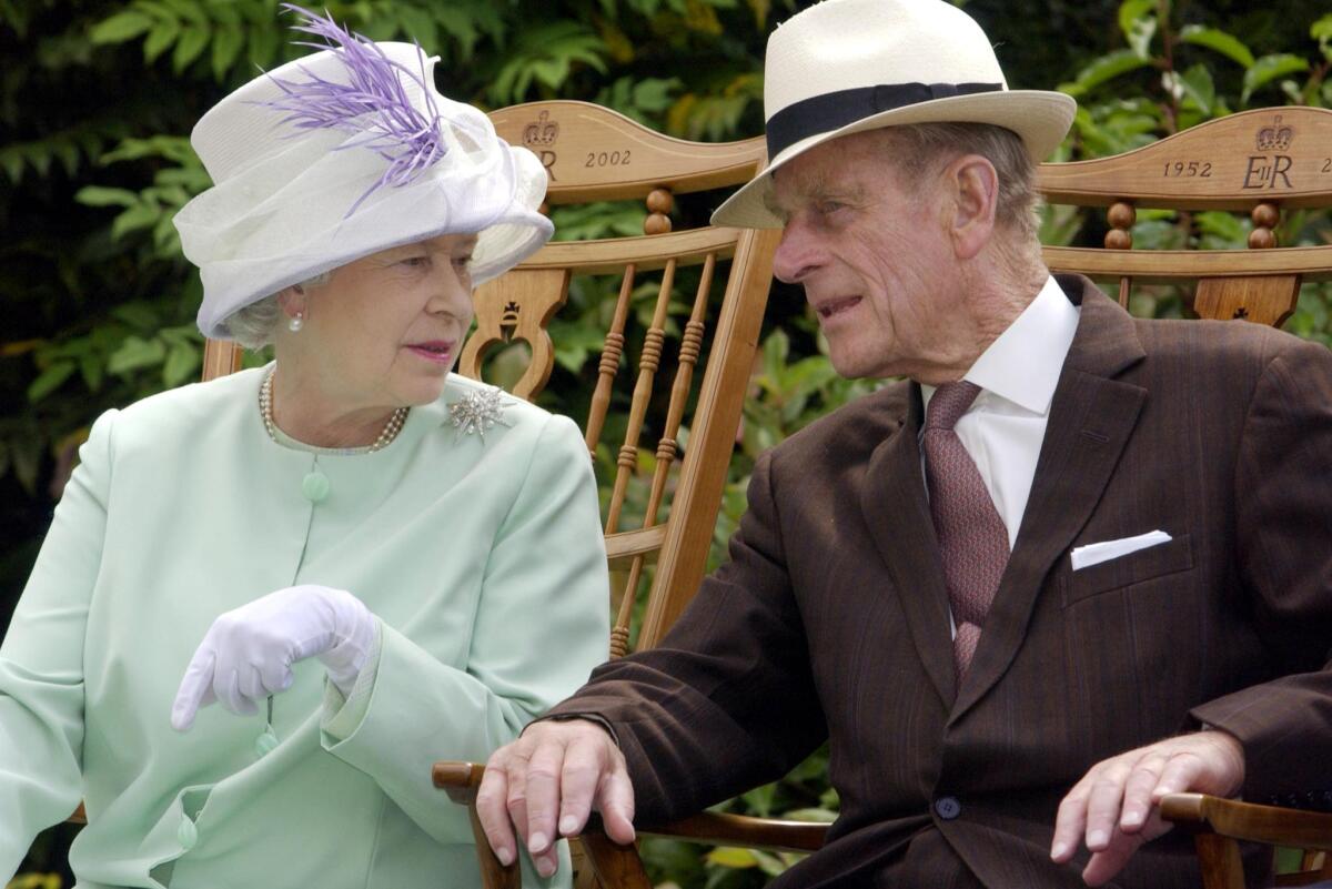 Prince Philip leans over slightly to address Queen Elizabeth II