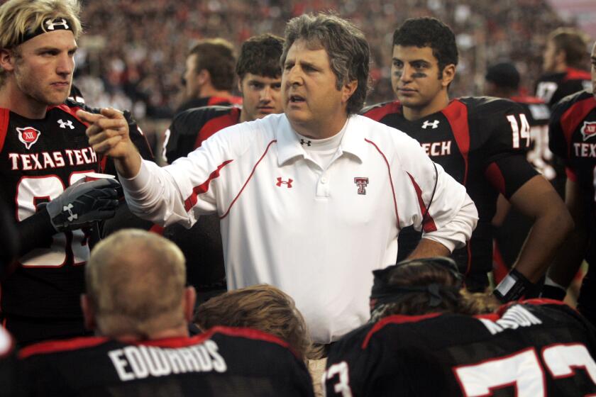 Mike Leach is shown talking with Texas Tech players on the sidelines during a 2009 game