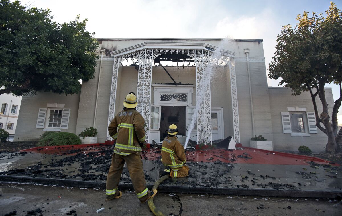Los Angeles County firefighters hose down the still-smoldering Good Shepherd Bible Church in Whittier.