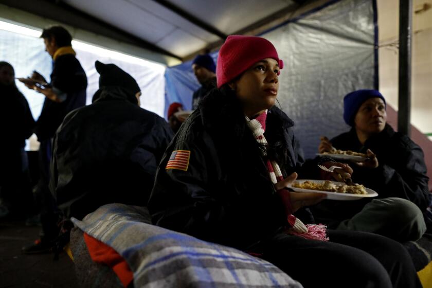 MATAMOROS, TAMAULIPAS -- MONDAY, NOVEMBER 12, 2018: Jessica Zamora, 18, of Havana, Cuba, who is pregnant, seeking political asylum, eats a meal prepared by Brendon Tucker, 23, of Canyon Lake, Texas, while camping along with other immigrants outside Mexicos' National Institute of Migration office at the Gateway International Bridge in Matamoros, Tamaulipas, on Nov. 12, 2018. Volunteers from the U.S. feed immigrants seeking asylum who are camping out along the U.S. - Mexico border at the Gateway International Bridge in Matamoros, Tamaulipas. (Gary Coronado / Los Angeles Times)