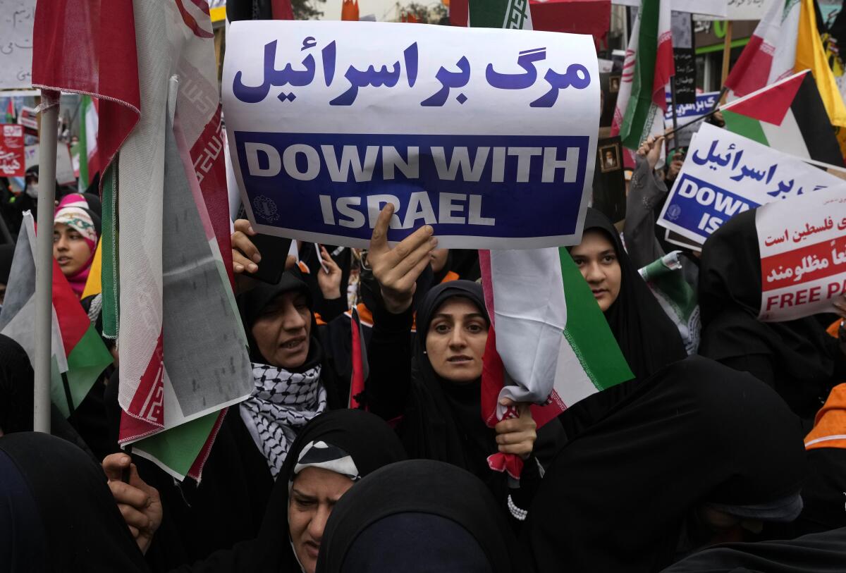 Una manifestante iraní sostiene un cartel antiisraelí durante un acto frente a la antigua embajada