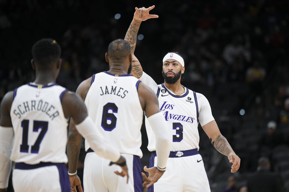 The Lakers' Anthony Davis (3) celebrates with LeBron James and Dennis Schroder on Nov. 25, 2022.