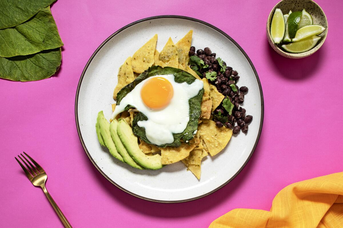 Chilaquiles verdes: tortilla chips under green sauce and a fried egg, with avocado slices