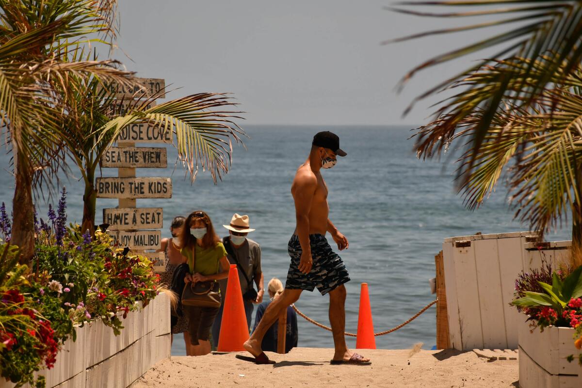 Bathers and onlookers arrive at Malibu's Paradise Cove with masks on July 13.