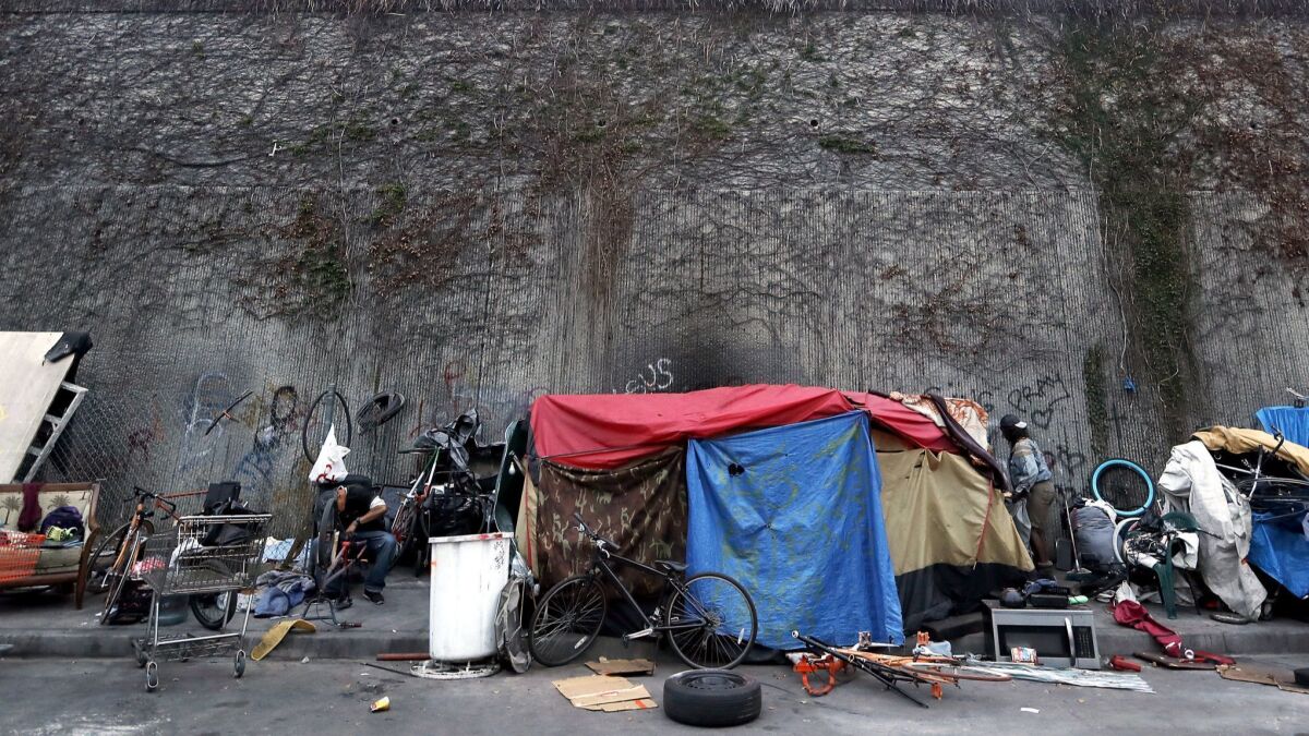 Homeless people live in tents beside a wall that separates Grand Avenue and the Harbor Freeway in South L.A. on May 22.