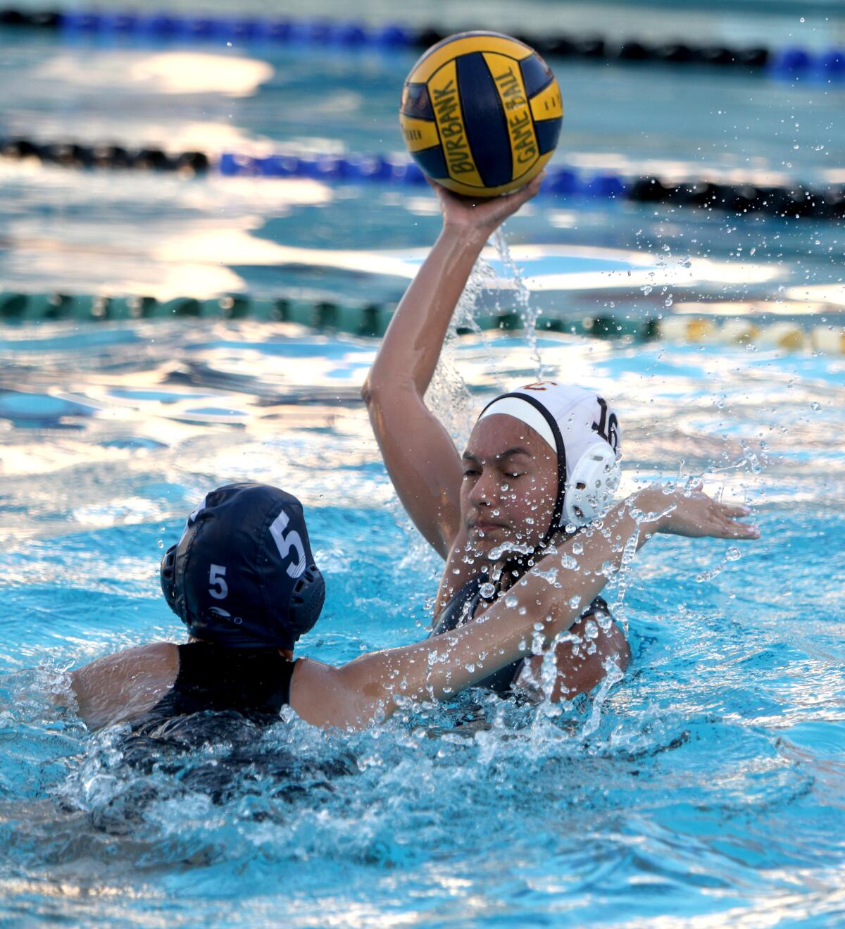 La Canada High School water polo player Meadow Solares passes the ball under pressure from Michele Mirzoyan in non-league game vs. Burbank High in Burbank on Thursday, Dec. 12, 2019.