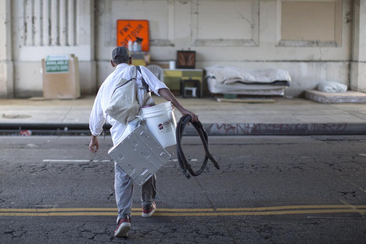 Fernando Lopez carries possessions to his street side encampment under a freeway overpass in Los Angeles on Nov. 20.