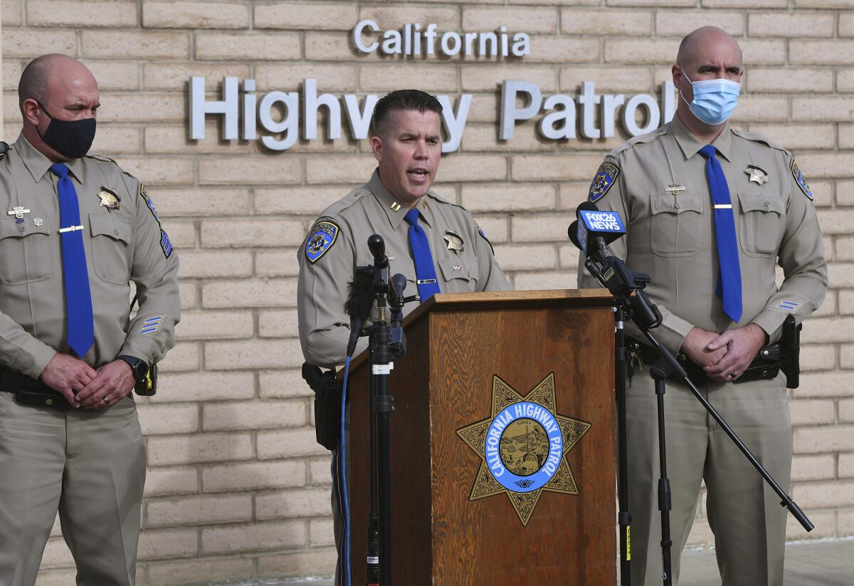 Three highway patrol officers stand at a lectern with the CHP logo in front of microphones