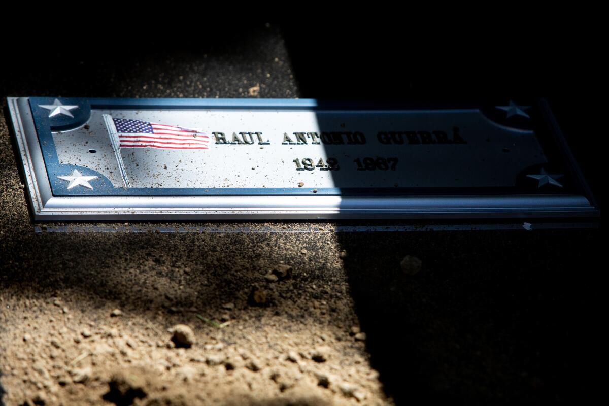 Dirt covers Raul Guerra's casket after it is lowered into the ground during a burial service at Rose Hill Memorial Park.(Dania Maxwell / Los Angeles Times)