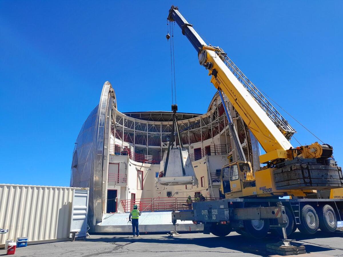 A crane extracting the last piece of the base of the Caltech Submillimeter Observatory's telescope
