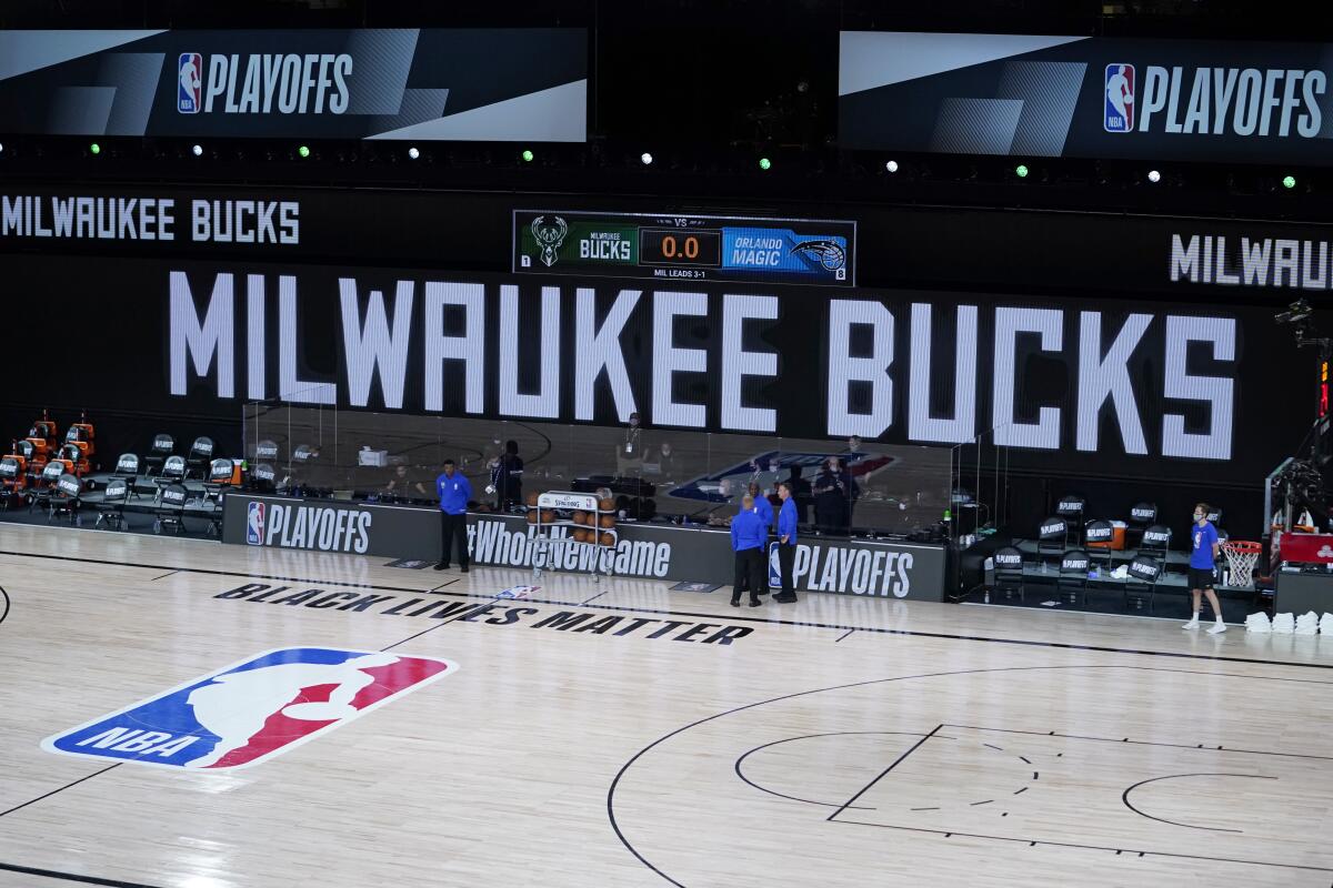 Officials stand beside an empty court at the scheduled start between the Milwaukee Bucks and the Orlando Magic.