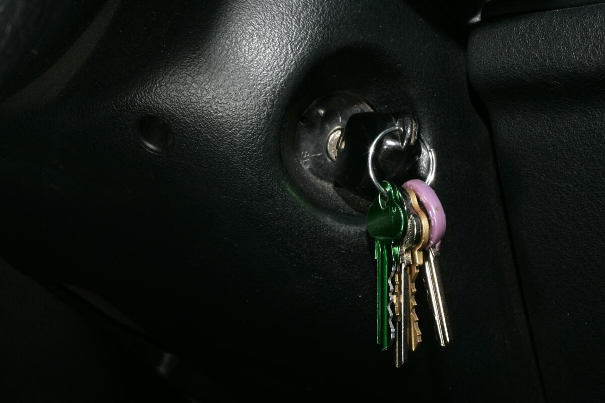 A car key in the ignition of a vehicle, with other keys dangling from the keychain