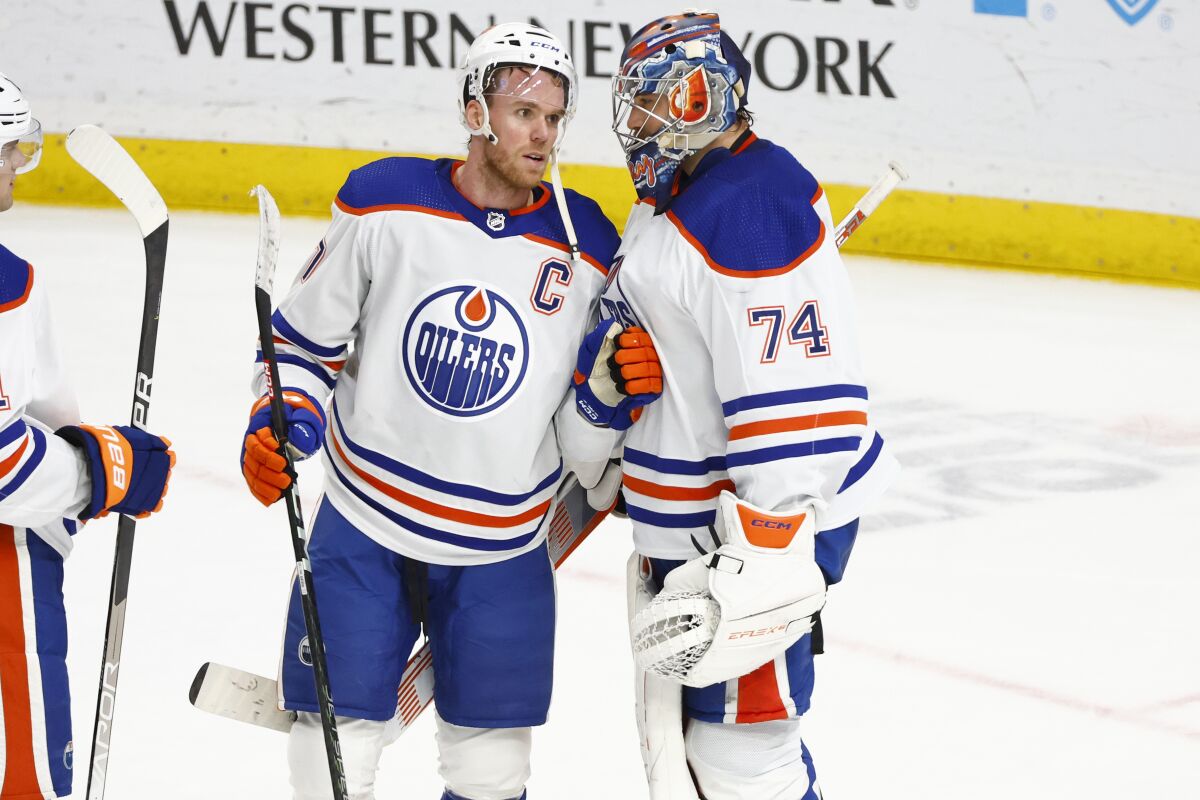 Edmonton Oilers center Connor McDavid and goaltender Stuart Skinner (74) celebrate a 3-2 following the third period of an NHL hockey game against the Buffalo Sabres, Monday, March 6, 2023, in Buffalo, N.Y. (AP Photo/Jeffrey T. Barnes)