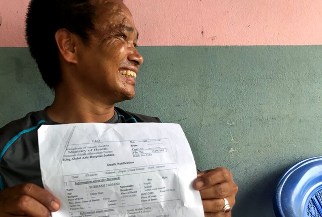 Subash Tamang holds his own death certificate from Saudi Arabia, sitting on his porch in Laxmimarga, Nepal.