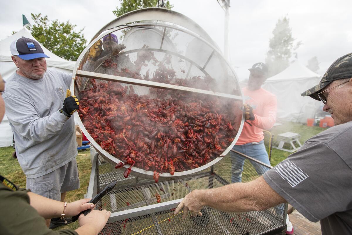 Troy Hassett, left, and Isaiah Dotson, center, transfer freshly cooked crawfish into a wagon during the Crawfish Festival.