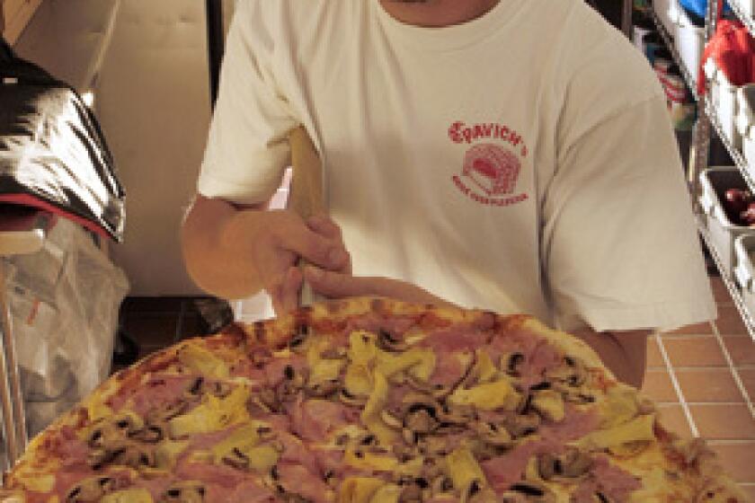 Angelo Vukelja holds an A Quattro Gusti pizza topped with mushrooms, artichokes, ham and cheese at Pavich's Brick Oven Pizzeria in San Pedro.