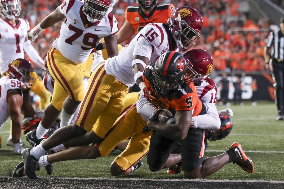 Oregon State running back Deshaun Fenwick scores a touchdown as he's tackled by USC's Eric Gentry and Anthony Beavers Jr.