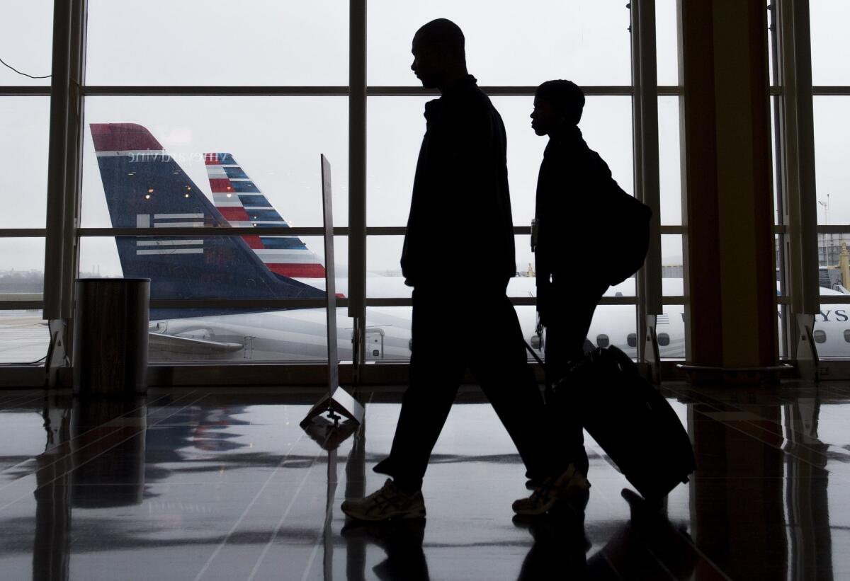 Passengers walk through the terminal as they head to their flights at Reagan National Airport in Arlington, Va., on Dec. 23, 2015. Three of the nation's biggest carriers were sued by travel agents who accuse the airlines of conspiring to keep fares high on multi-city trips.