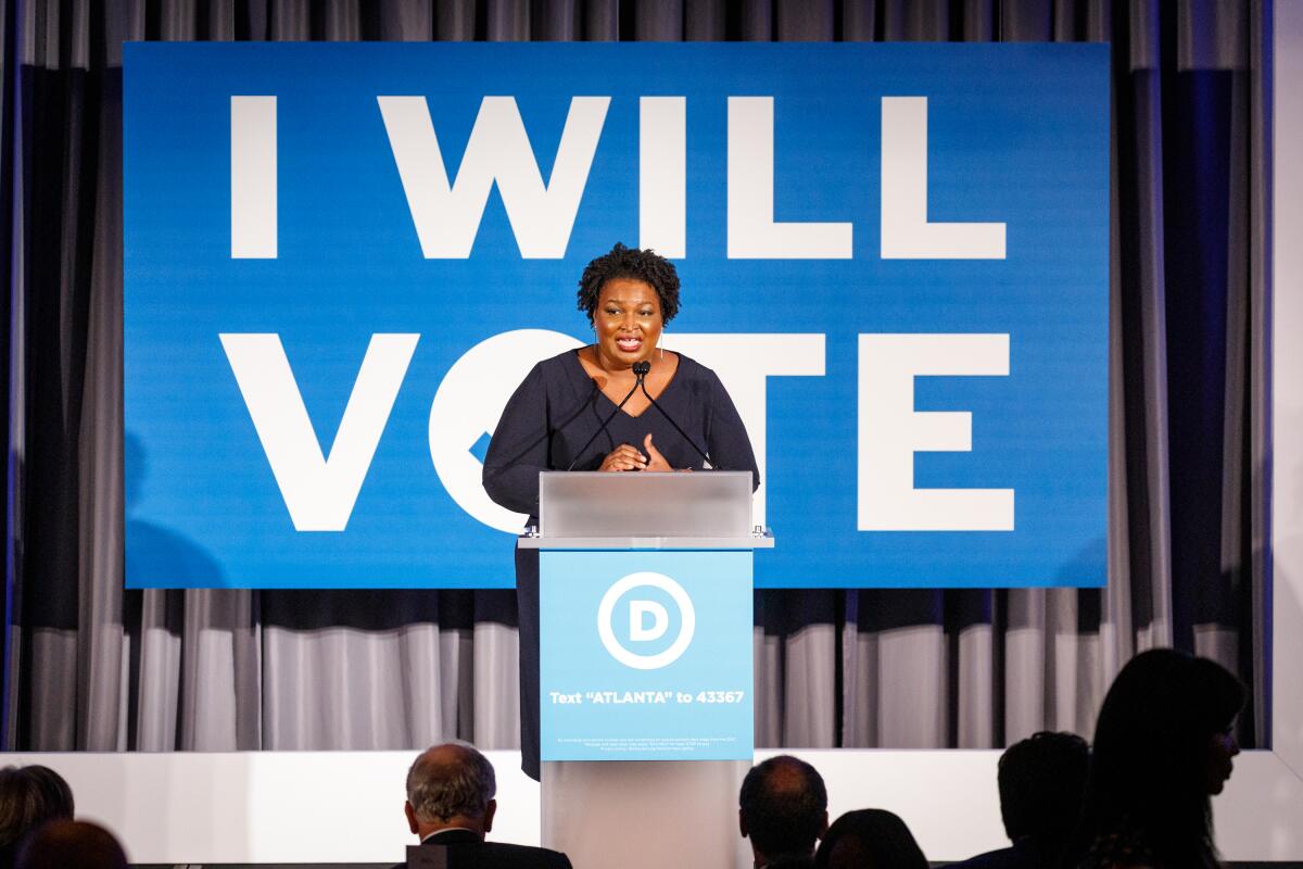Stacey Abrams, behind a podium, speaks to a crowd at a Democratic National Committee event.