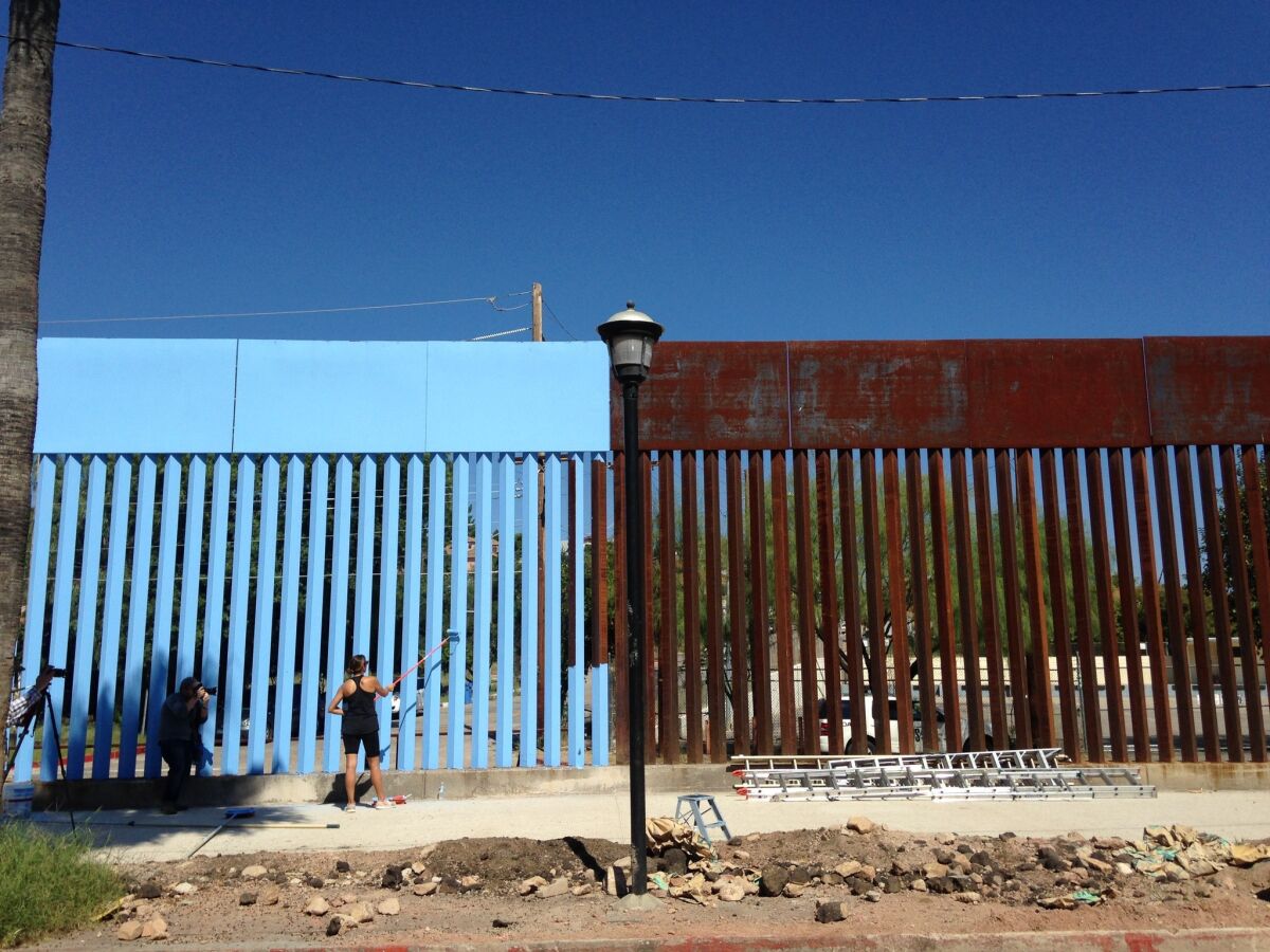 Artist Ana Teresa Fernandez paints the U.S.-Mexico border wall blue to "lower the sky" as part of the art installation, "Borrando la Frontera," or "Erasing the Border," in Nogales, Mexico, last week.