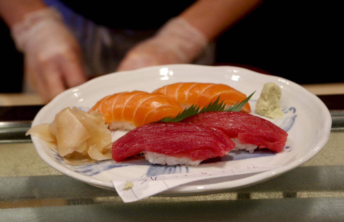 Gloves are worn to prepare sushi at Sushi Gen during their lunchtime rush hour in Los Angeles, but state lawmakers may repeal a law requiring food handlers wear gloves.