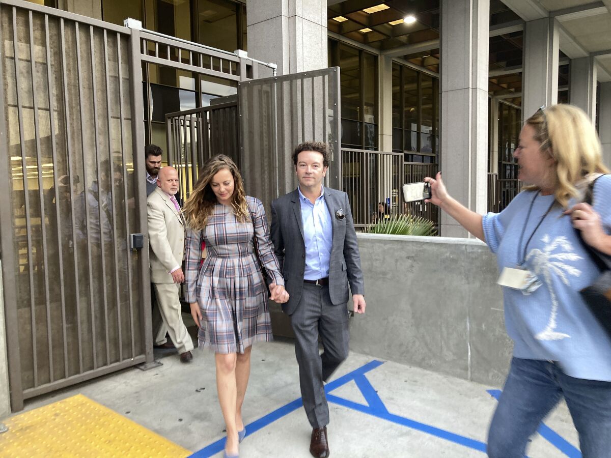 Two people walk away from a gate outside a building.