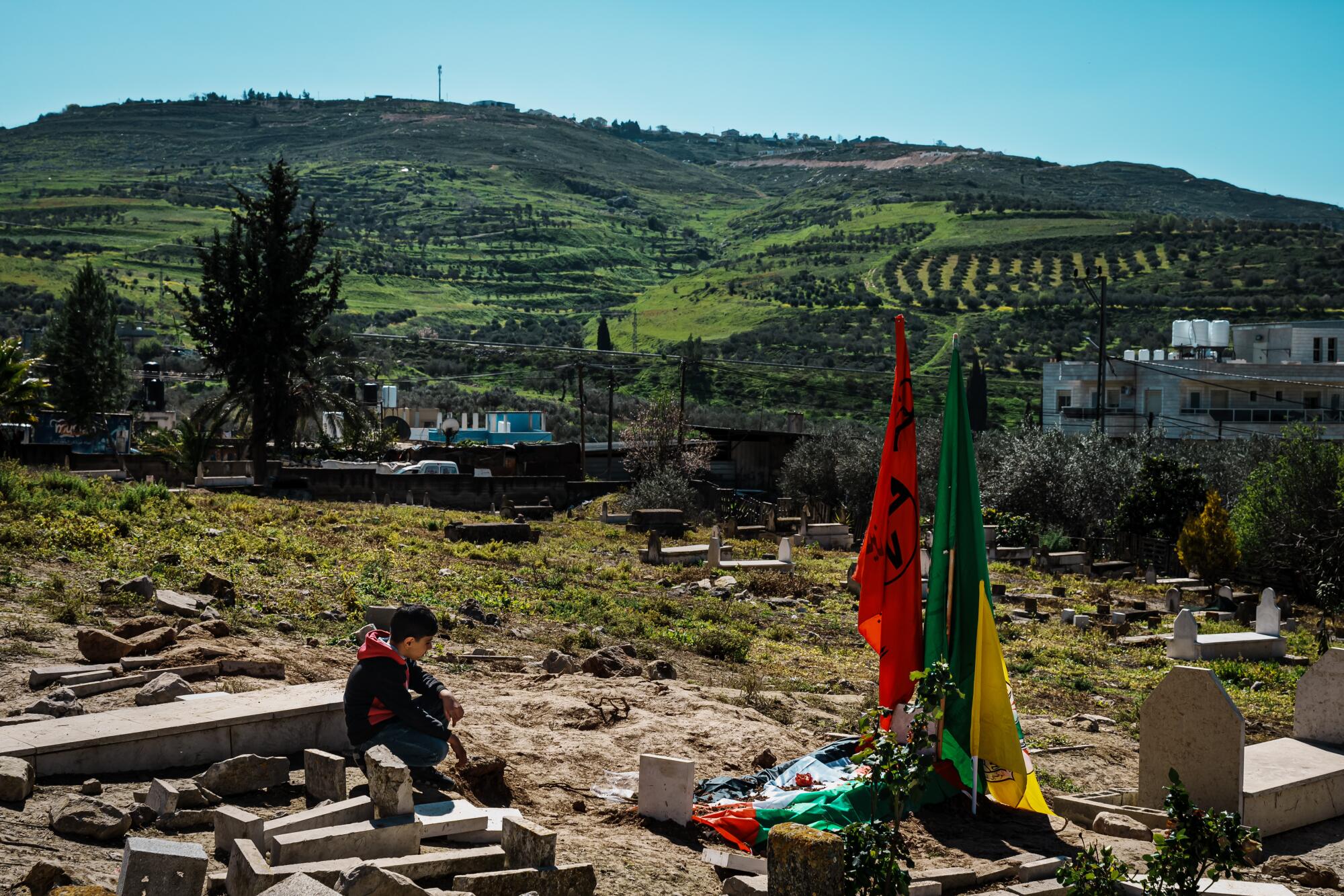 Seorang anak laki-laki duduk dengan tenang setelah pemakaman Amr Najjar.