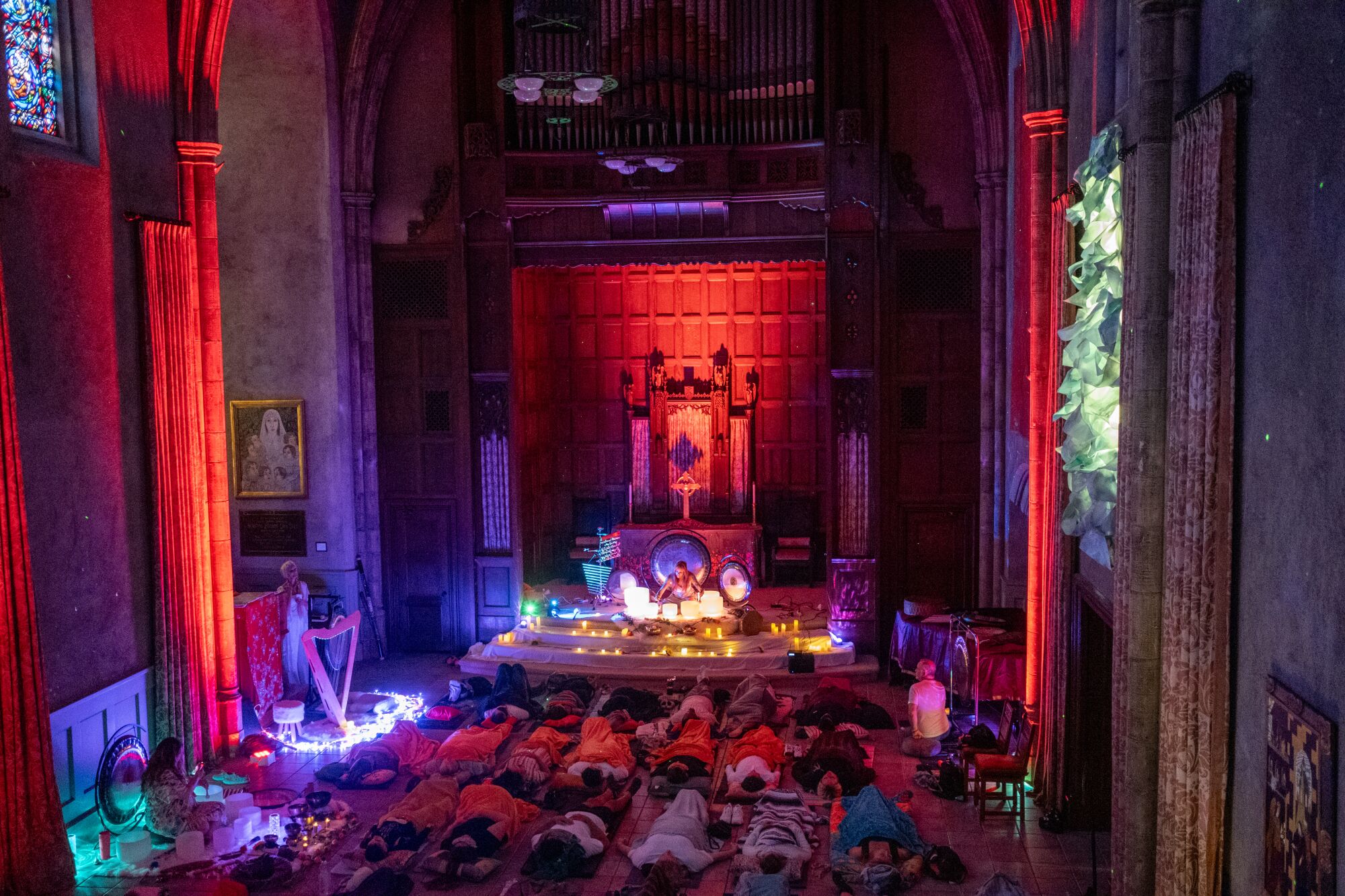 İnsanlar, ses banyosu için renkli üstten aydınlatma ve parlayan ışıklarla dekore edilmiş neo-gotik bir kilisede yerde yatıyordu.